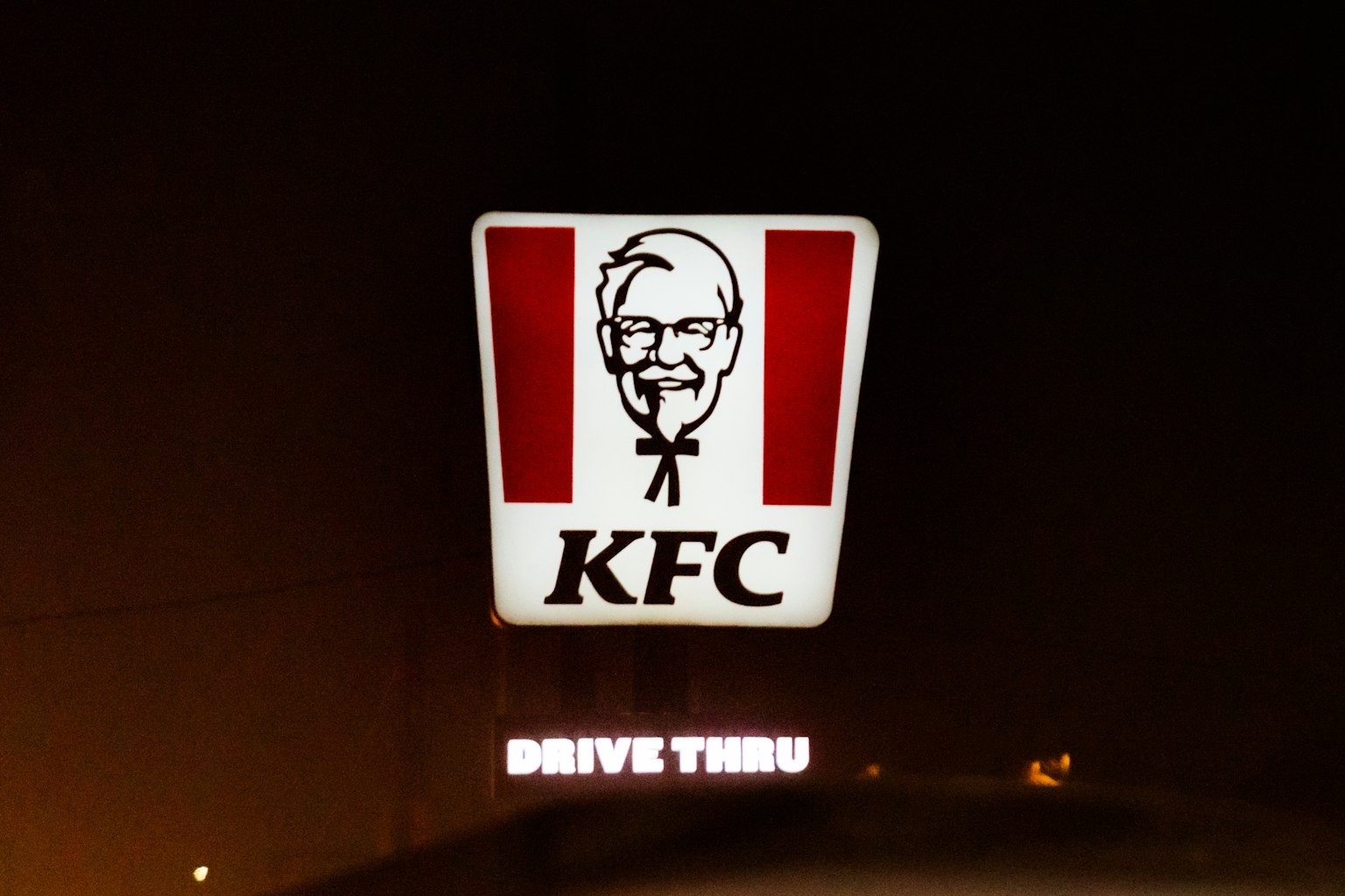 Verlicht KFC-logo met drive-thru-bord in het donker