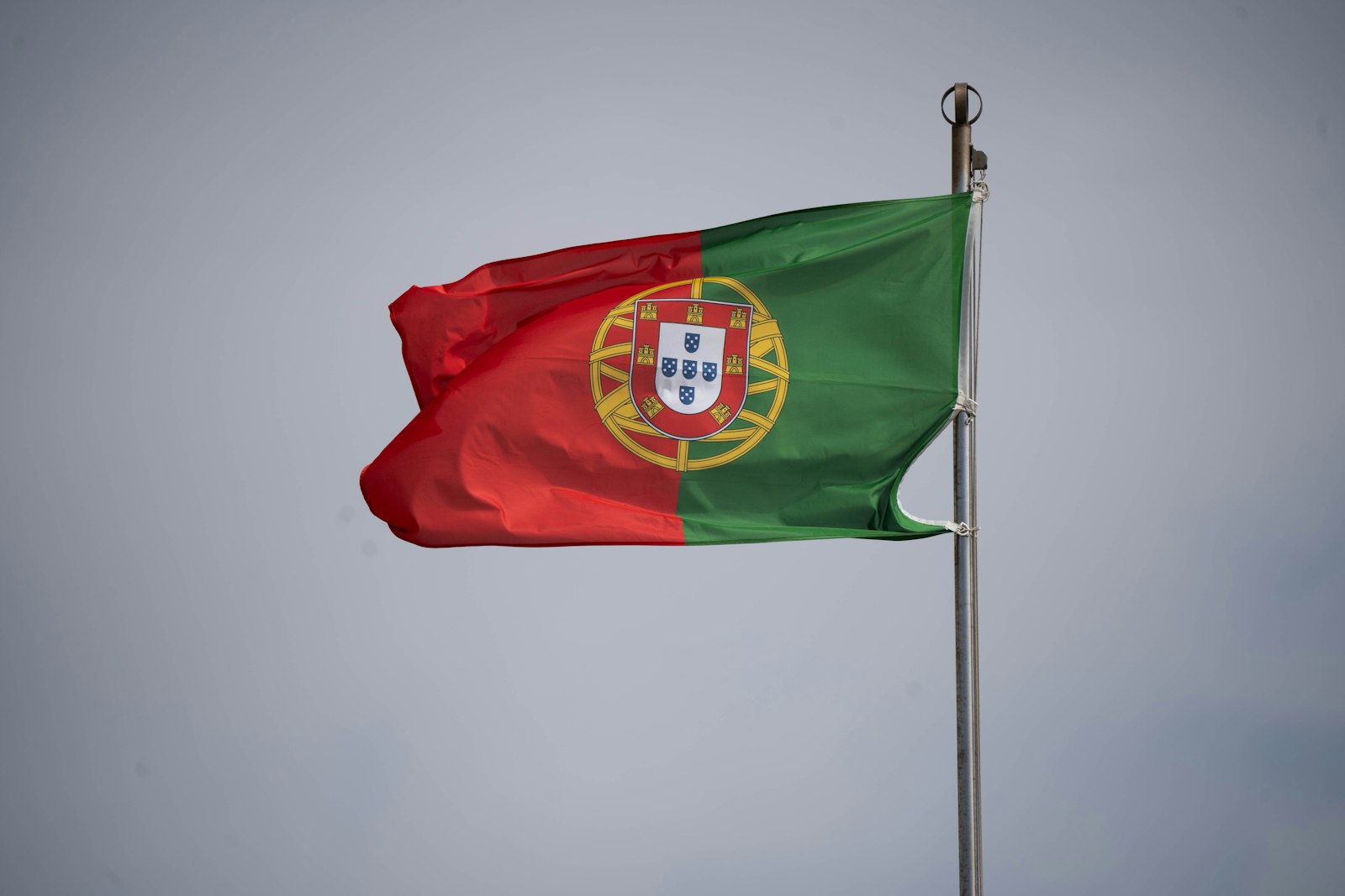 Portugese vlag wappert tegen een grijze lucht