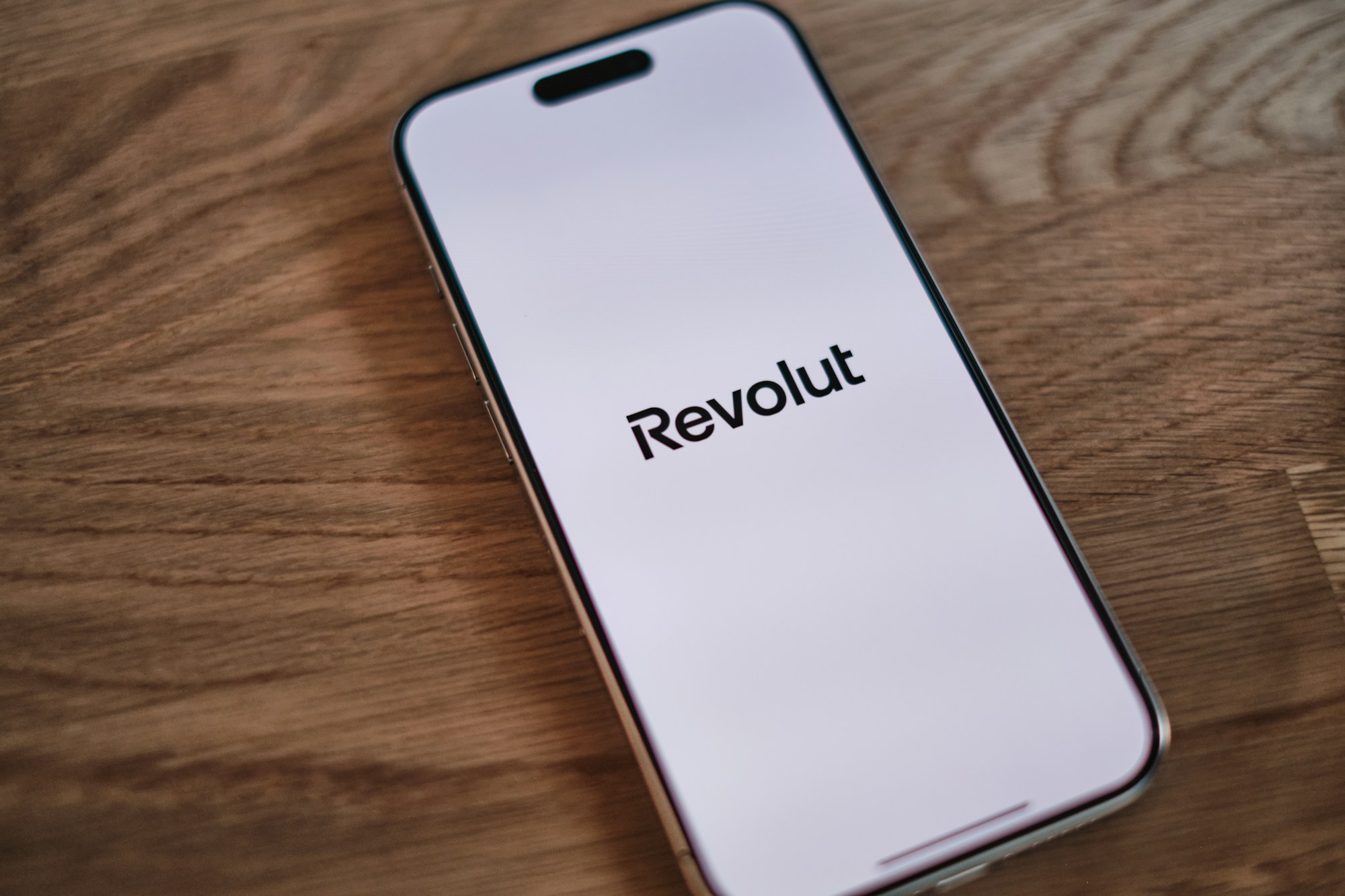 Smartphone met het logo van Revolut op een houten tafel